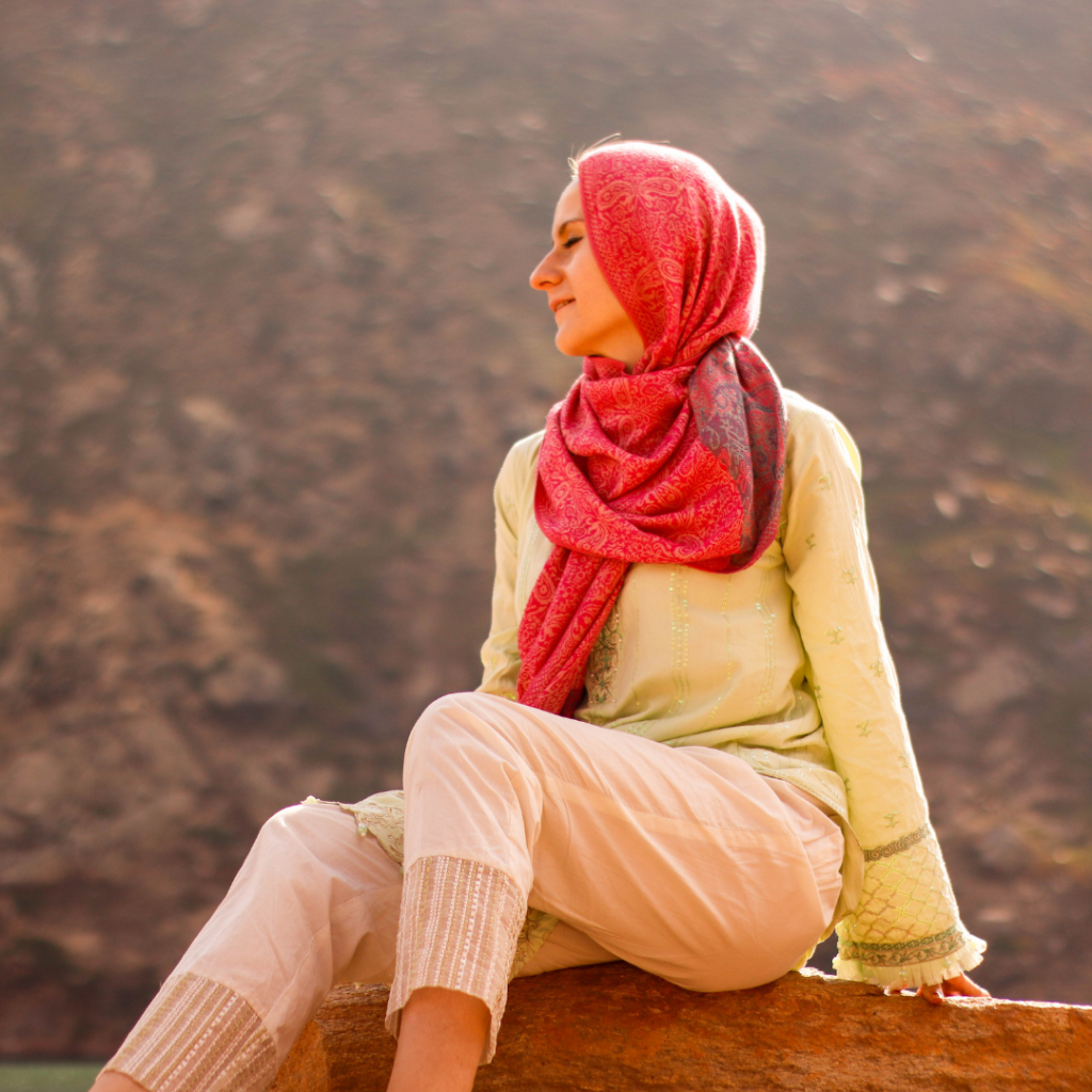 Girl sitting on a rock staring out into Lulusar Lake, Pakistan.