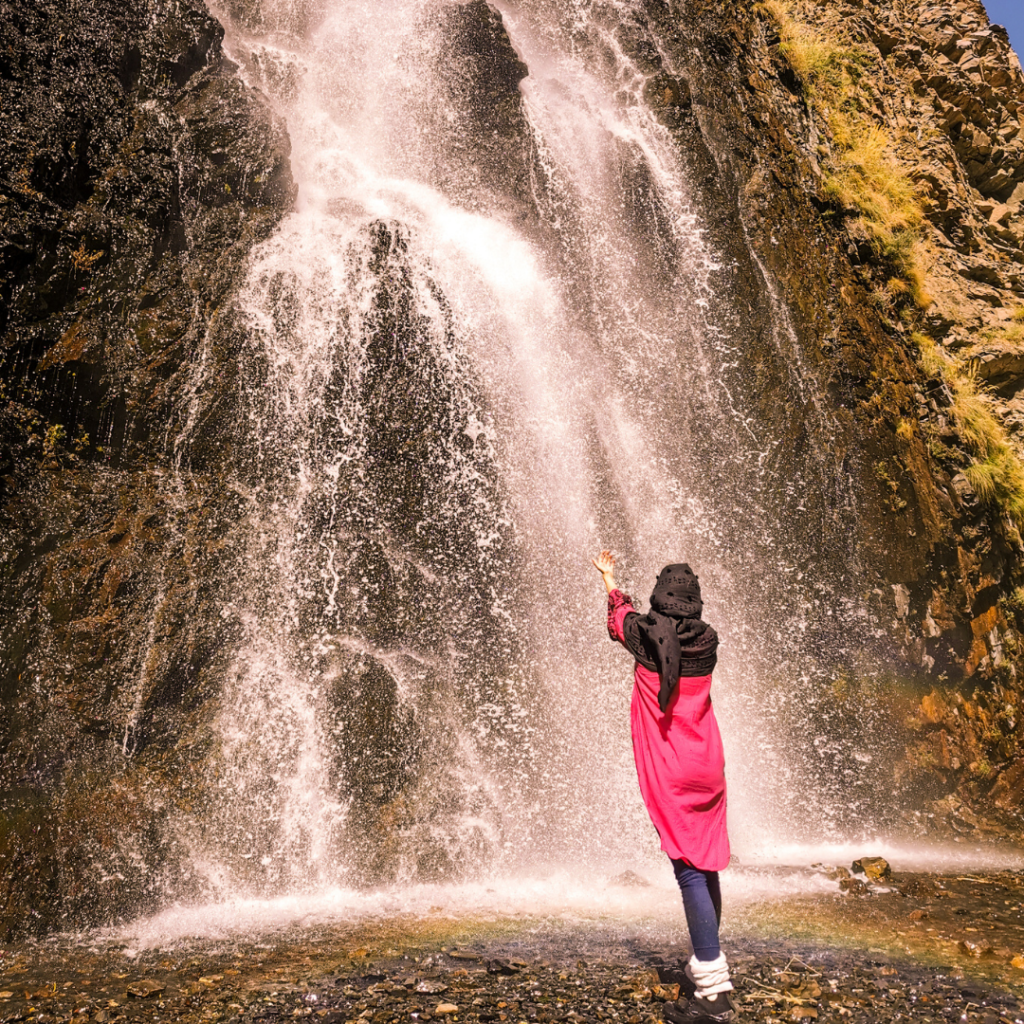 A Complete Travel Guide To Skardu, Pakistan 11 Girl trying to catch droplets in front of Manthoka Waterfall and a rainbow near Skardu, Pakistan.
