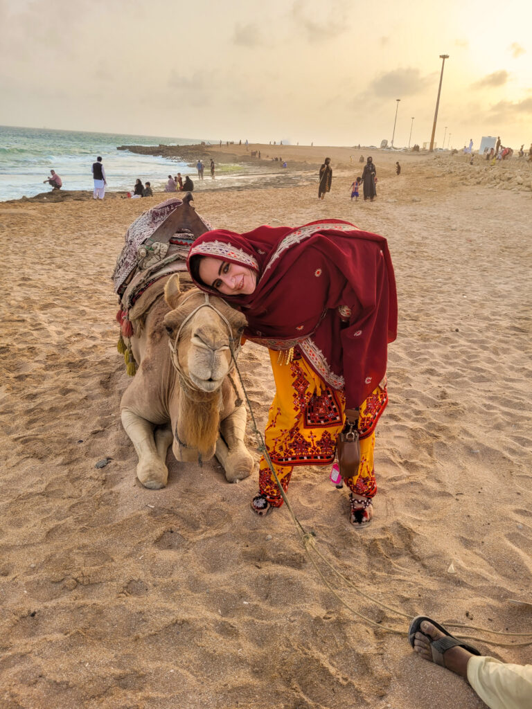 20 Stunning Places To Visit In Chabahar, Iran 9 Foreign girl in traditional Balochi dress hugging a camel at Darya Bozorg Beach in Chabahar, Balochistan, Iran.