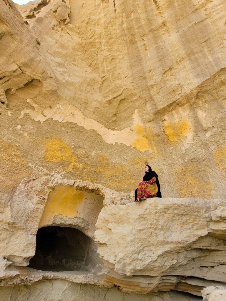 20 Stunning Places To Visit In Chabahar, Iran 12 Girl in Balochi dress sitting at the entrance of the Baan Mesiti Caves in Tis, Chabahar, Iran.