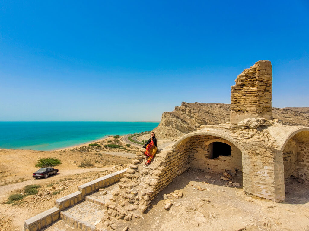 20 Stunning Places To Visit In Chabahar, Iran 13 Girl in Balochi dress sitting in the ruins of the Portuguese Castle overlooking the turquoise sea in Tis Village near Chabahar.